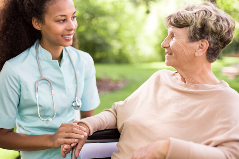 Caregiver sitting with an elderly patient outdoors