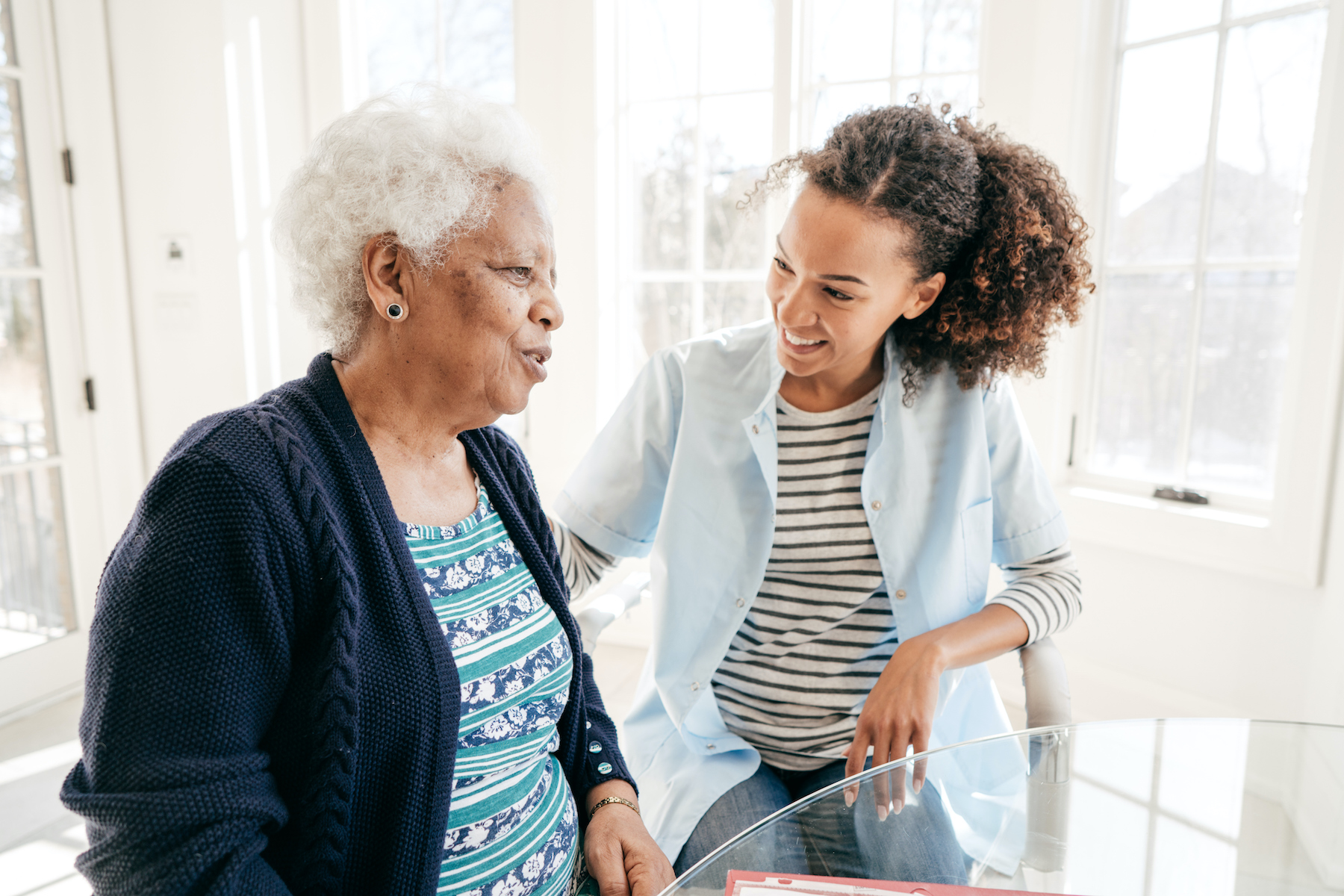 A healthcare service provider talking to a senior woman.