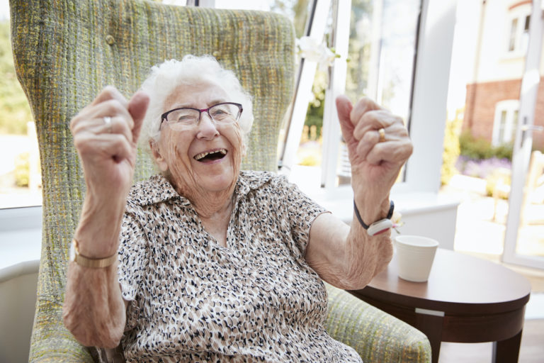 Excited senior woman sitting in chair