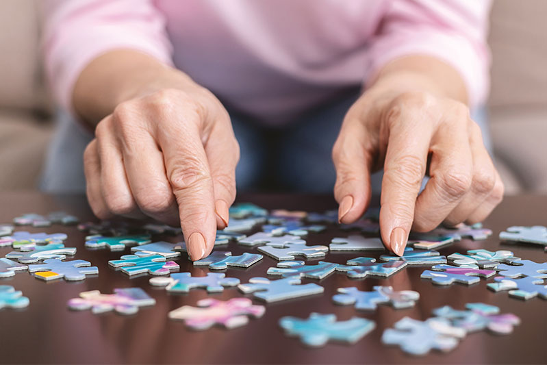 Senior woman hands working on puzzle