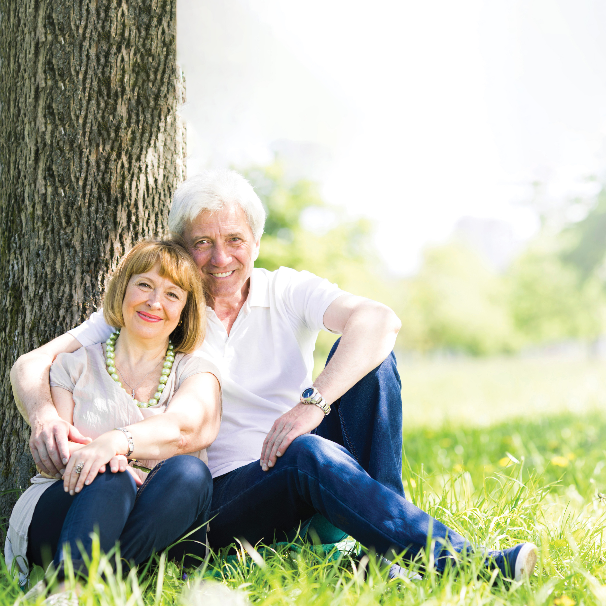 Senior couple sitting by tree
