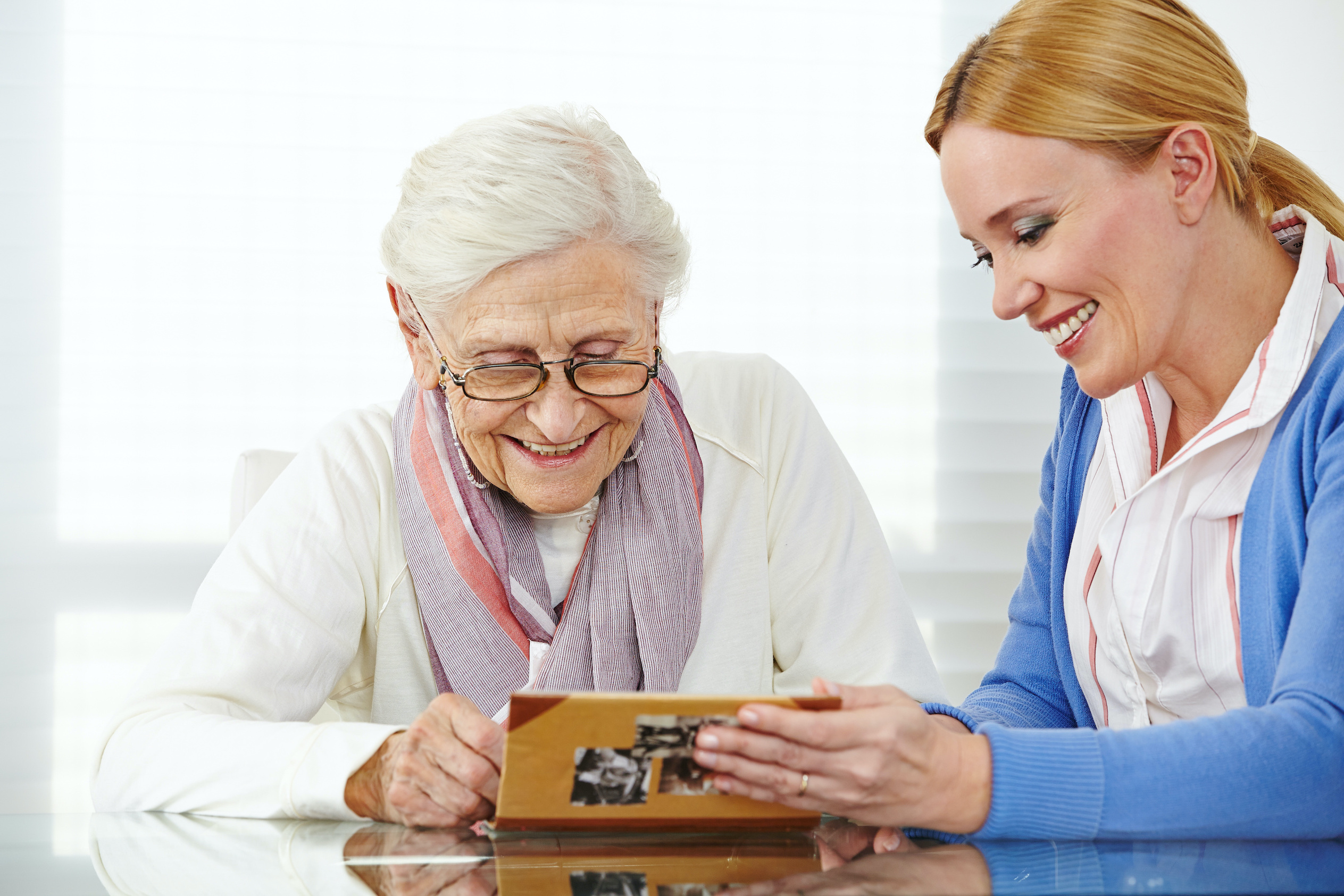 Mujer mayor y mujer de mediana edad mirando un álbum de fotos