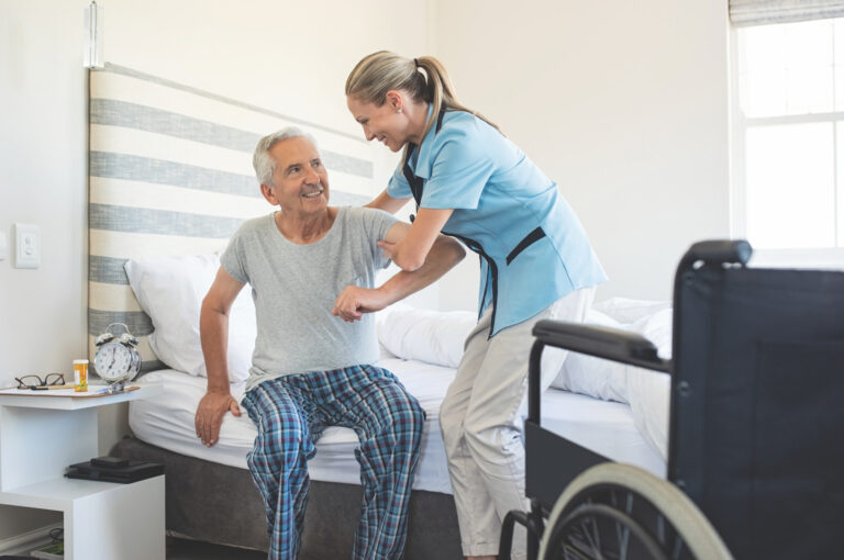 Nurse helping senior man out of bed