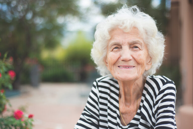 Senior woman sitting outdoors and smiling