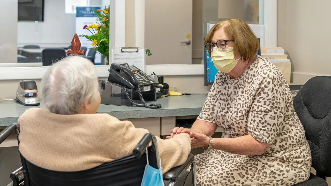 Staff member talking to a senior and holding her hand
