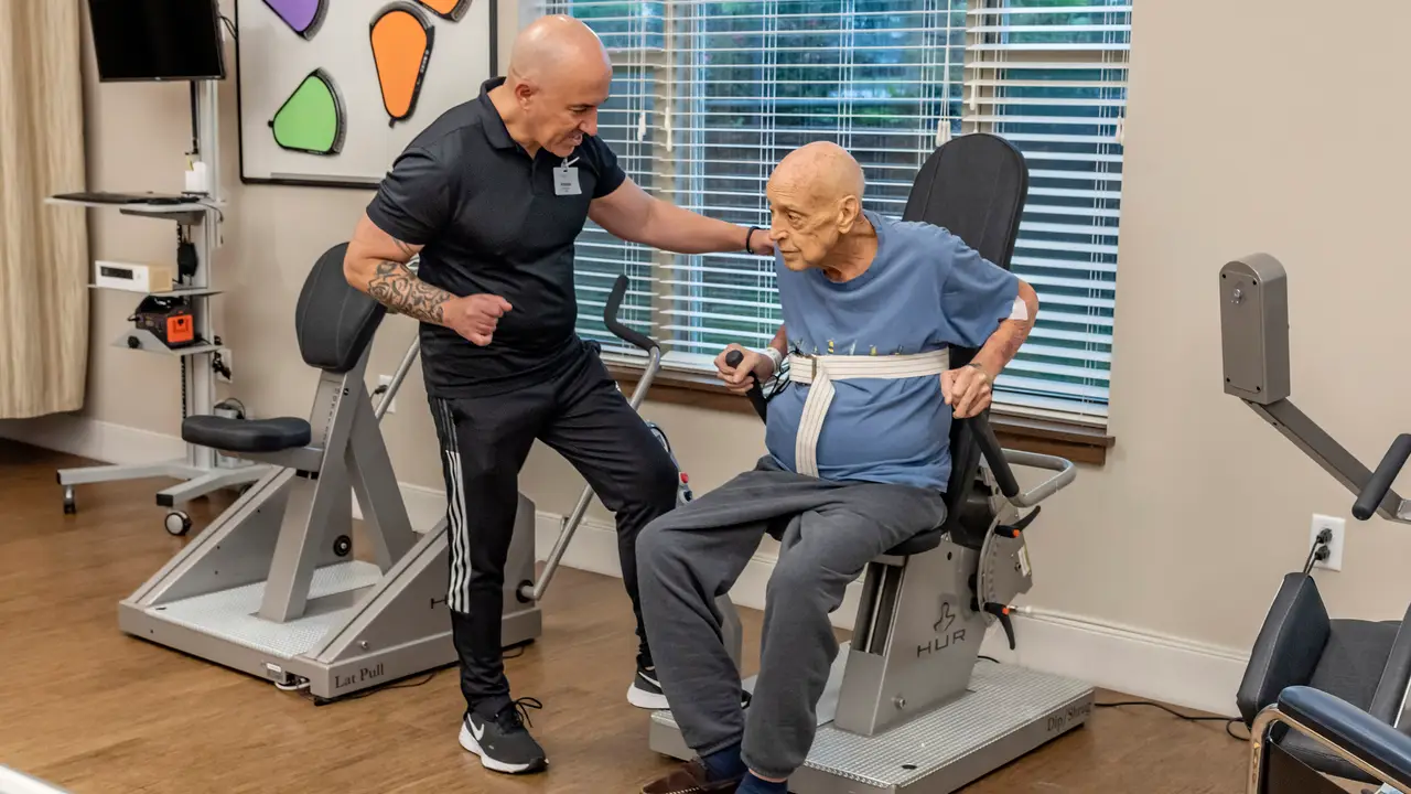 Therapist helping a patient use a arm machine