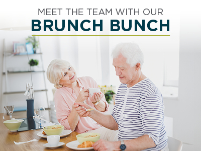 Two elderly individuals enjoy brunch at a dining table, smiling and engaging with each other. The text above them reads, 