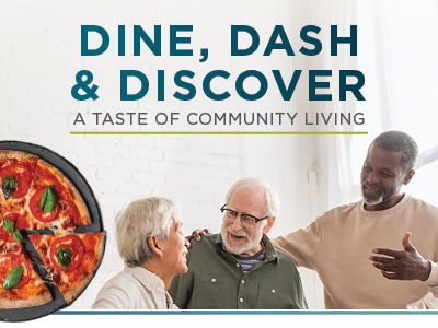 Three older adults smile and chat indoors, sharing friendship over pizza. Text above reads: “Dine, Dash & Discover – A Taste of Community Living.” Experience the warmth of assisted living in Prairie Village, KS.