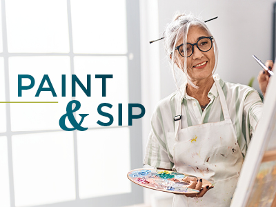 A smiling woman with gray hair in a bun and glasses paints on a canvas, holding a palette. She wears a paint-stained apron. Text on the image reads 