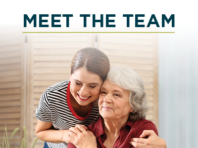 A young woman hugs an older woman from behind and smiles. The older woman has gray hair and a gentle expression. The text above them reads