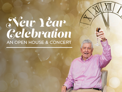 An older man in a pink shirt smiles and raises a glass in a toast. Behind him is a large clock and the text