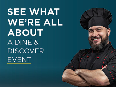 A smiling male chef in a black uniform and hat stands with arms crossed next to text: 