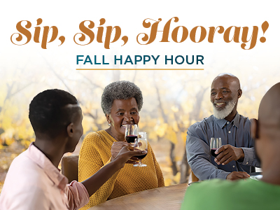 Four people sit around a table toasting with drinks, smiling and enjoying each other's company. The text above them reads, “Sip, Sip, Hooray! FALL HAPPY HOUR.” Autumn colors and trees are visible in the background.