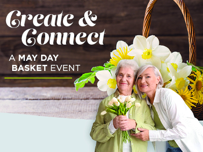 Two smiling older women from assisted living stand together holding flowers in front of a large basket filled with white and yellow blooms. Text reads:
