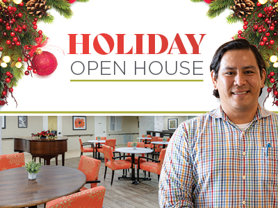 A man in a plaid shirt smiles in front of a festive