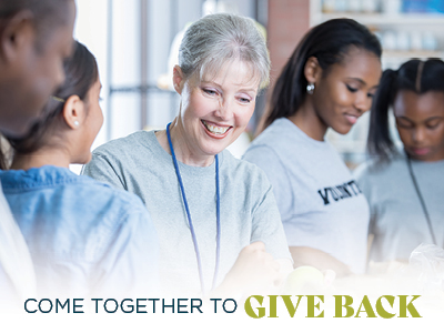 A smiling older woman and three young adults, wearing volunteer shirts, work together. The text reads, 