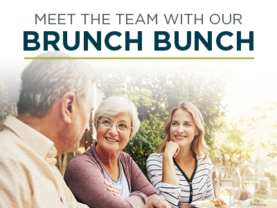 Three people—two women and one man—sit at a table outdoors, smiling and talking. The text above them reads, 