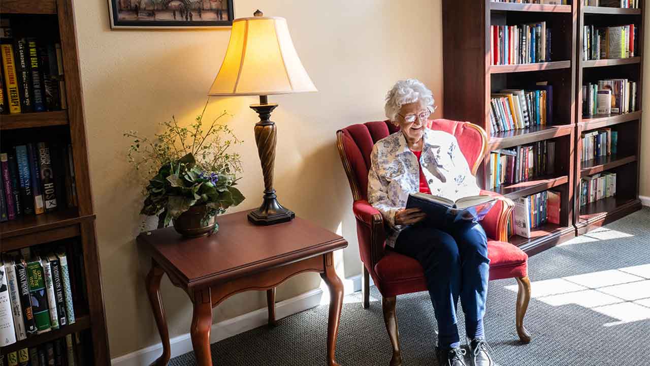 Resident reading a book in the library at Eiler Senior Living