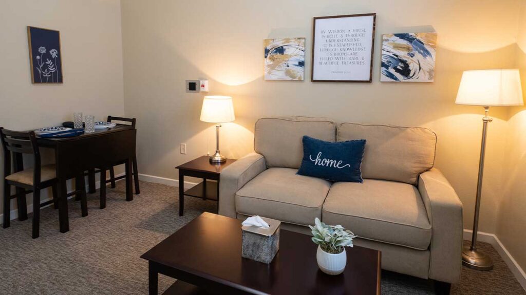 A warmly lit living room with a beige sofa adorned with a blue