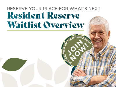 Smiling older man in a plaid shirt stands next to a green badge that says