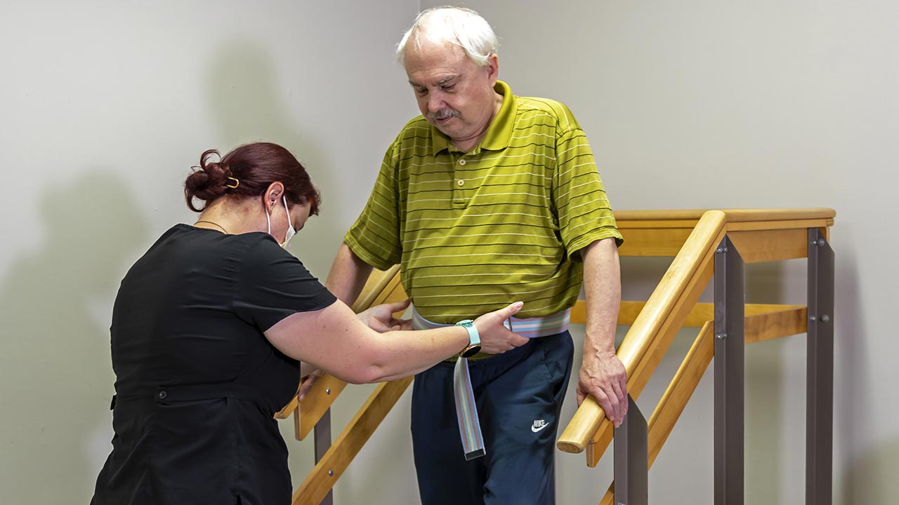 Meridian therapist helping senior male walk down stairs