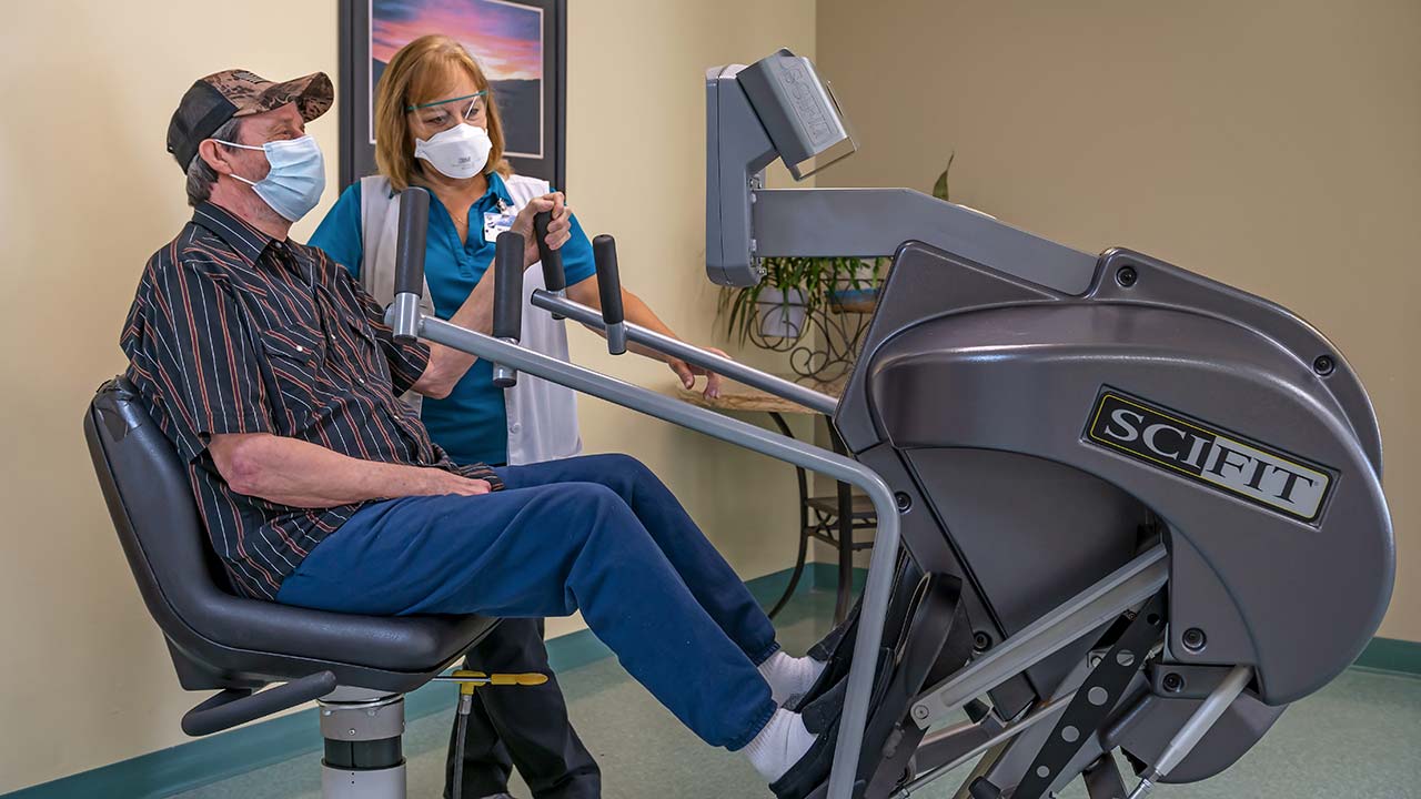 Fair Oaks physical therapist helping patient on cycle machine