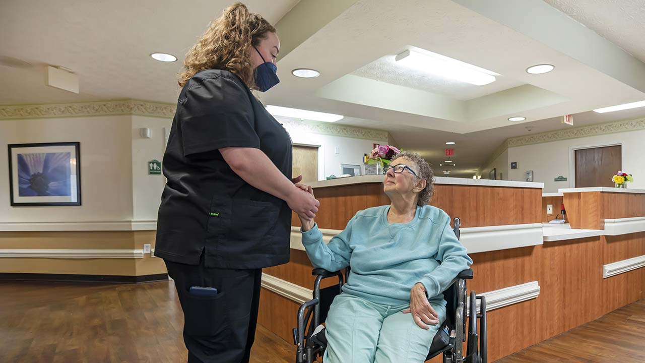 Charlton Place staff holding residents hand at front desk