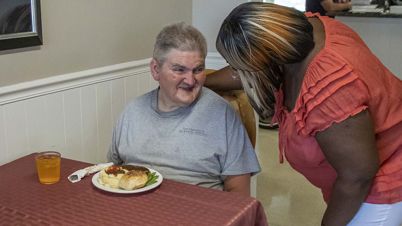 Highland staff talking to a resident eating lunch in the dining room
