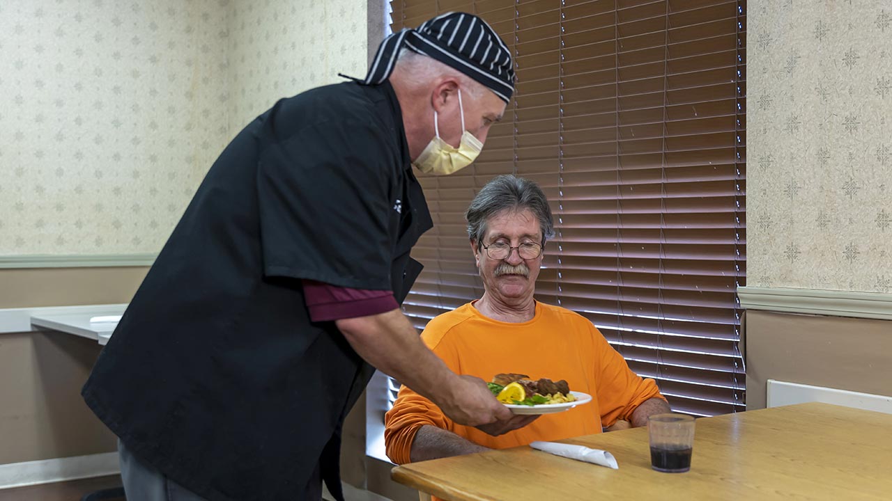 Meridian senior male resident being served lunch by staff