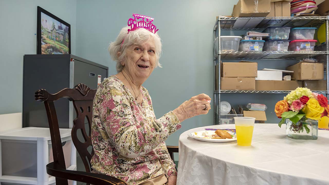 Charlton Place resident eating lunch on her birthday with a tiara