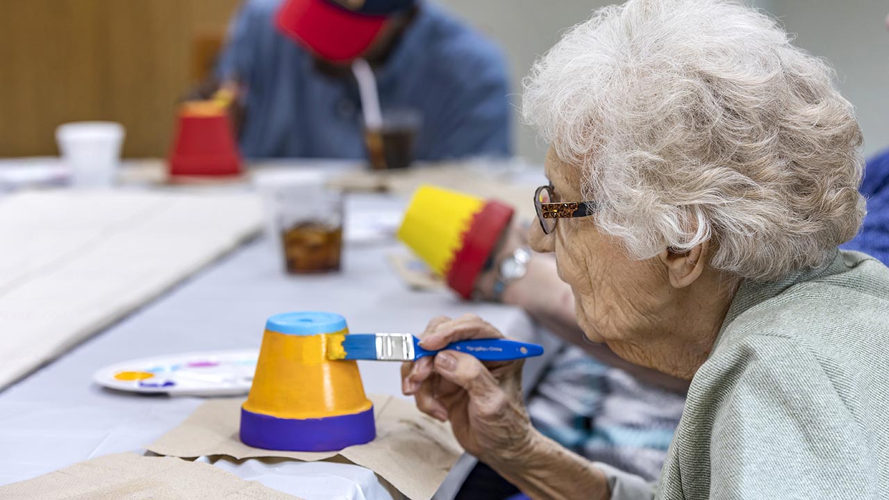 Carlinville patient in art class painting flower pots