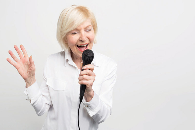 Senior woman singing into microphone
