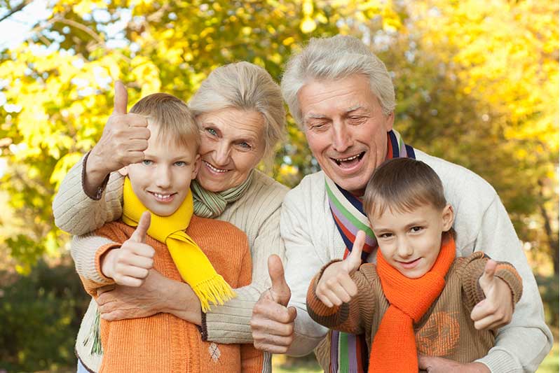 Grandparents with grandsons giving thumbs up while outside