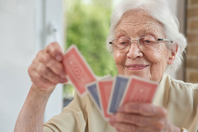 Senior woman holding red and blue playing cards in her hands