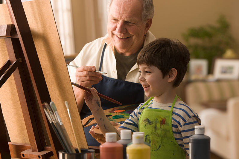 Senior man and young boy painting on easel