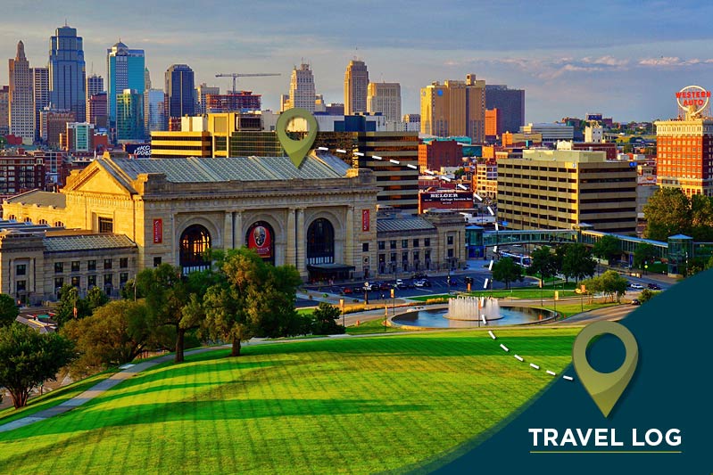 A cityscape view featuring a large historic building with a tall, modern skyline in the background. The scene includes a lush green park with a fountain in the foreground. Two location markers and a "Travel Log" label are visible on the image.