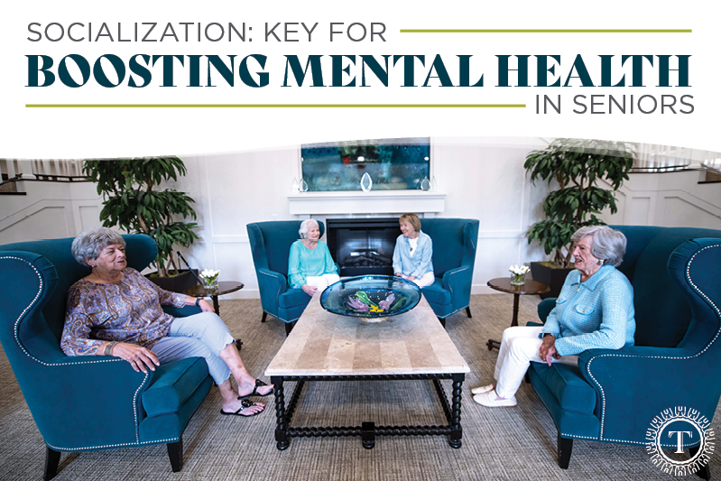 Four seniors sit in armchairs around a coffee table, engaging in conversation.