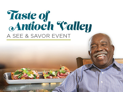 Smiling man sitting beside a tray of gourmet appetizers. Text reads: “Taste of Antioch Valley: A See & Savor Event.”.