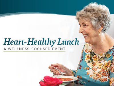 Older woman with short gray hair, wearing a floral blouse, smiles while eating soup. Text reads: