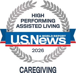 A gray laurel wreath surrounds the text "High Performing Assisted Living." Below is a blue ribbon with "U.S. News & World Report 2026." At the bottom, it says "Caregiving.