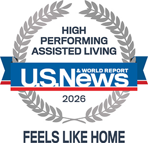 A gray laurel wreath surrounds the text "High Performing Assisted Living," with a blue, red, and white banner reading "U.S. News & World Report 2026." Below, it says "Feels Like Home.