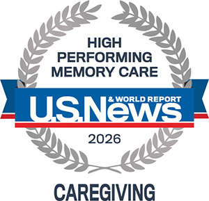A badge with laurel leaves reads "High Performing Memory Care, U.S. News & World Report, 2026, Caregiving" in blue, white, and gray colors.
