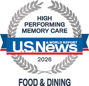 A silver laurel wreath surrounds the text “High Performing Memory Care” above the U.S. News & World Report logo. Below it reads “2026” and “Food & Dining.” The colors are blue, red, silver, and white.