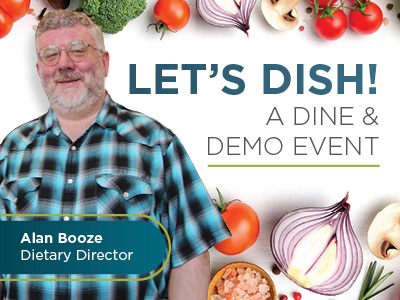 A smiling man with gray hair and beard, wearing glasses and a blue plaid shirt, stands in front of a background with vegetables and text that reads, “LET’S DISH! A DINE & DEMO EVENT.” A label names him as Alan Booze, Dietary Director.