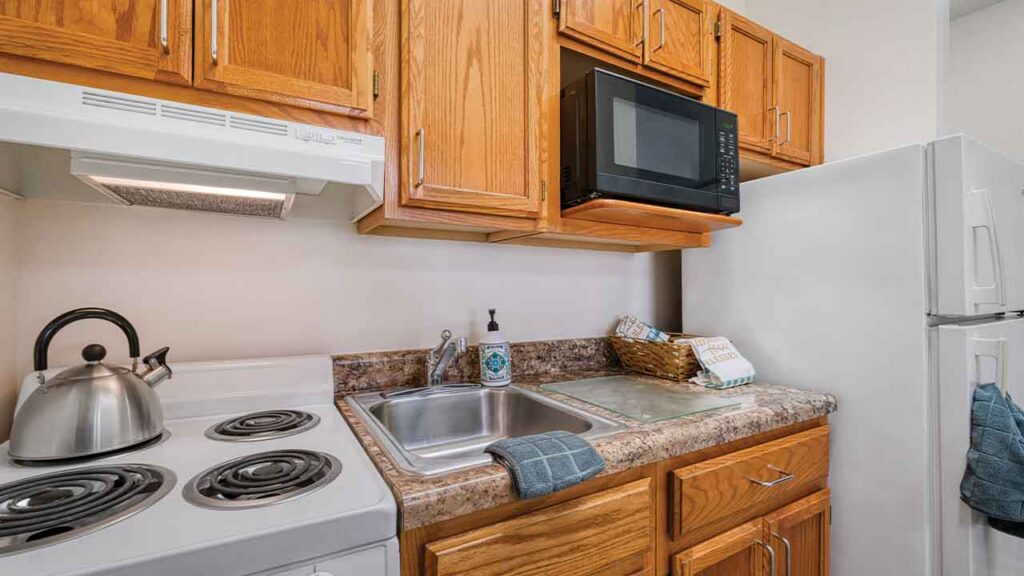 Kitchen counter with a stainless steel sink, electric stove with a kettle, and an over-the-range microwave.