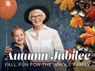 Smiling elderly woman and young girl holding a balloon, surrounded by autumn leaves, acorns, and pinecones. Text reads: “Autumn Jubilee. Fall fun for the whole family.”.