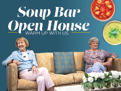 Two older women sit on a beige sofa, smiling, with bowls of soup above them. Text reads, “Soup Bar Open House. Warm up with us,” on a blue background. A white flower arrangement sits on a table in front.