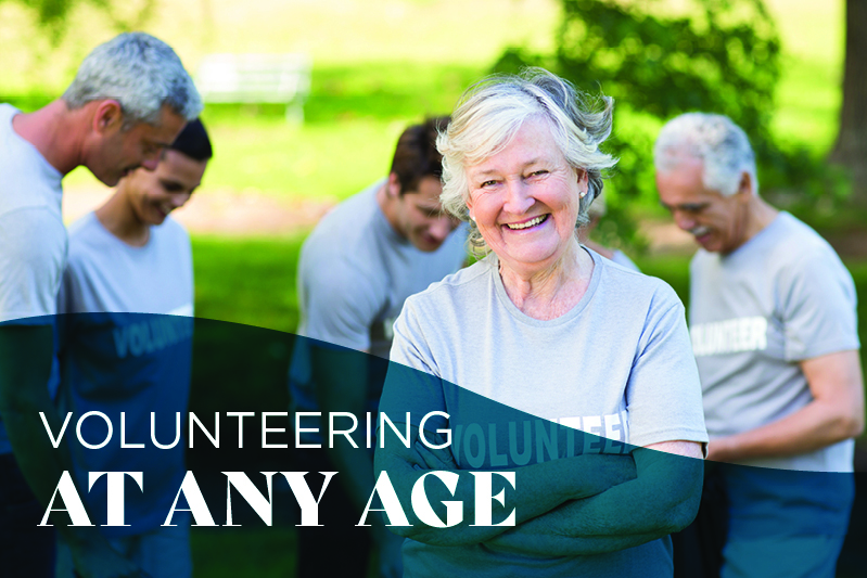 A smiling older woman in a gray “volunteer” shirt stands in front of a group of diverse adults outdoors, with the text “Volunteering at any age” overlayed on the image.