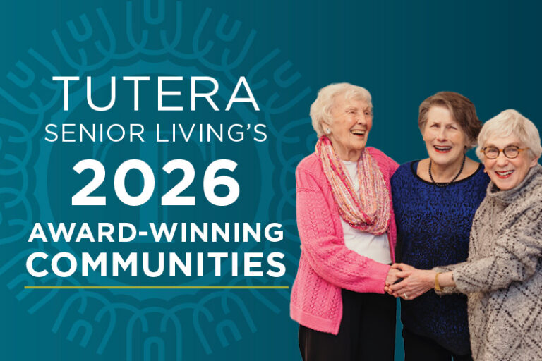 Three smiling elderly women stand together, holding hands, in front of text that reads: “Tutera Senior Living’s 2026 Award-Winning Communities” on a blue background with a decorative circular pattern.