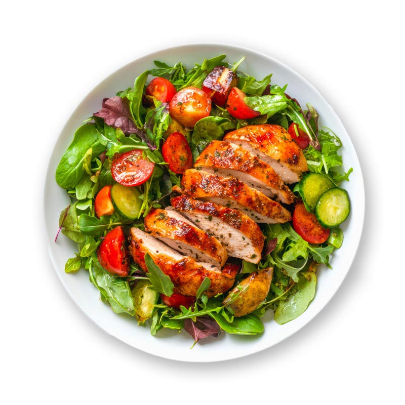 A white plate filled with mixed greens, cherry tomatoes, cucumber slices, and roasted potato pieces, topped with sliced grilled chicken breast.